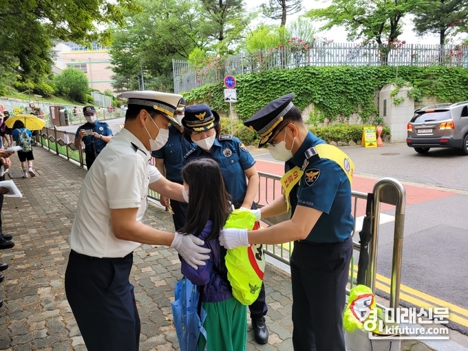 군포경찰서 관계자들이 능내초등학교에서 등교하는 초등학생에게 가방덮게를 씌워주고 있다. <사진=군포경찰서> 
