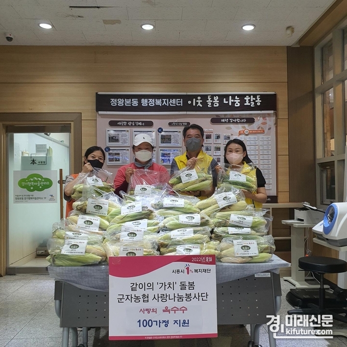 군자농협사랑나눔봉사단은 시흥시 정왕본동에 사랑의 옥수수를 기증하고 관계자들과 기념촬영을 하고 있다. <사진=시흥시>