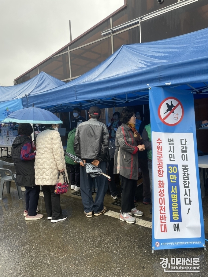 지난 29일 비가 내리는 궂은 날씨에도 불구하고 시민들이 수원전투비행장 화성시 이전 반대 서명을 하기 위해 줄을 서 있다. <사진=범대위>