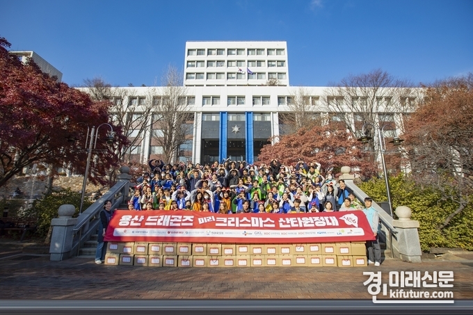 지난 4일 '미리 크리스마스 산타 원정대'에 참여한 용산 드래곤즈 봉사자들이 용산 지역 아동복지시설 어린이들에세 크리스마스 선물을 전달하고 기념사진을 촬영하고 있다. <사진=CGV>