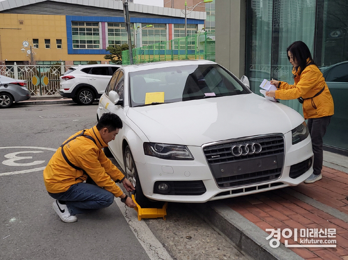 고양시 관계자들이 체납차량에 시금납부 안내문과 잠금장치를 채우고 있다. <사진=고양시>
