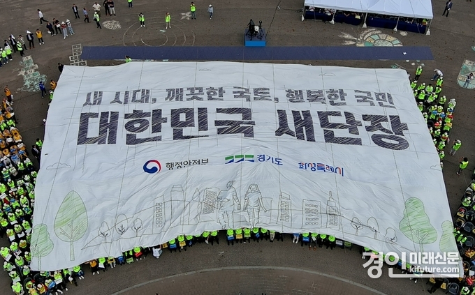 22일 대한민국 새단장 캠페인 행사 참석자들이 대형 현수막을 머리 위로 넘기며 ‘대한민국 새단장’ 퍼포먼스를 펼치고 있다. <사진=화성시>