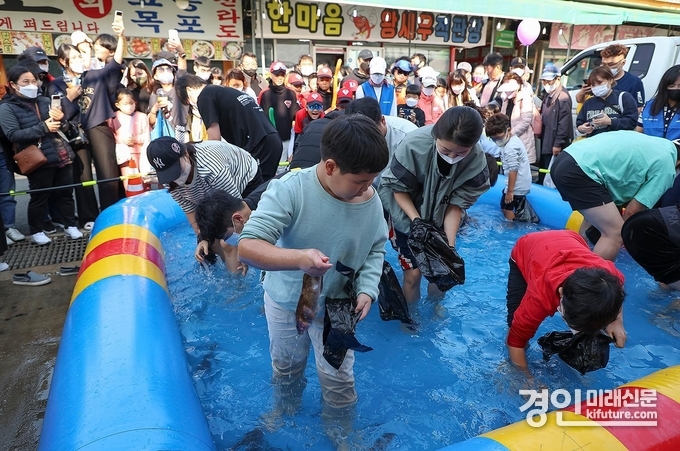 시민들이 제10회 시흥월곶포구축제 중 맨손 고기잡이 체험에 참여하고 있다. <사진=시흥시>