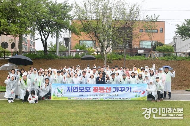 오산시 자연보호협의회 회원 100여 명이 오산천 꽃동산 가꾸기 행사에서 기념촬영을 하고 있다. <사진=오산시>